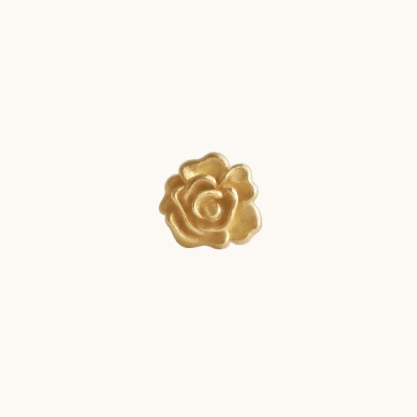 Gold rose-shaped earring on a white background